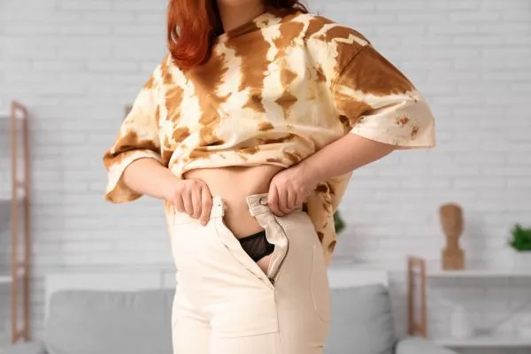 Image of woman trying to do her trousers up after pregnancy weight gain Sunninghill